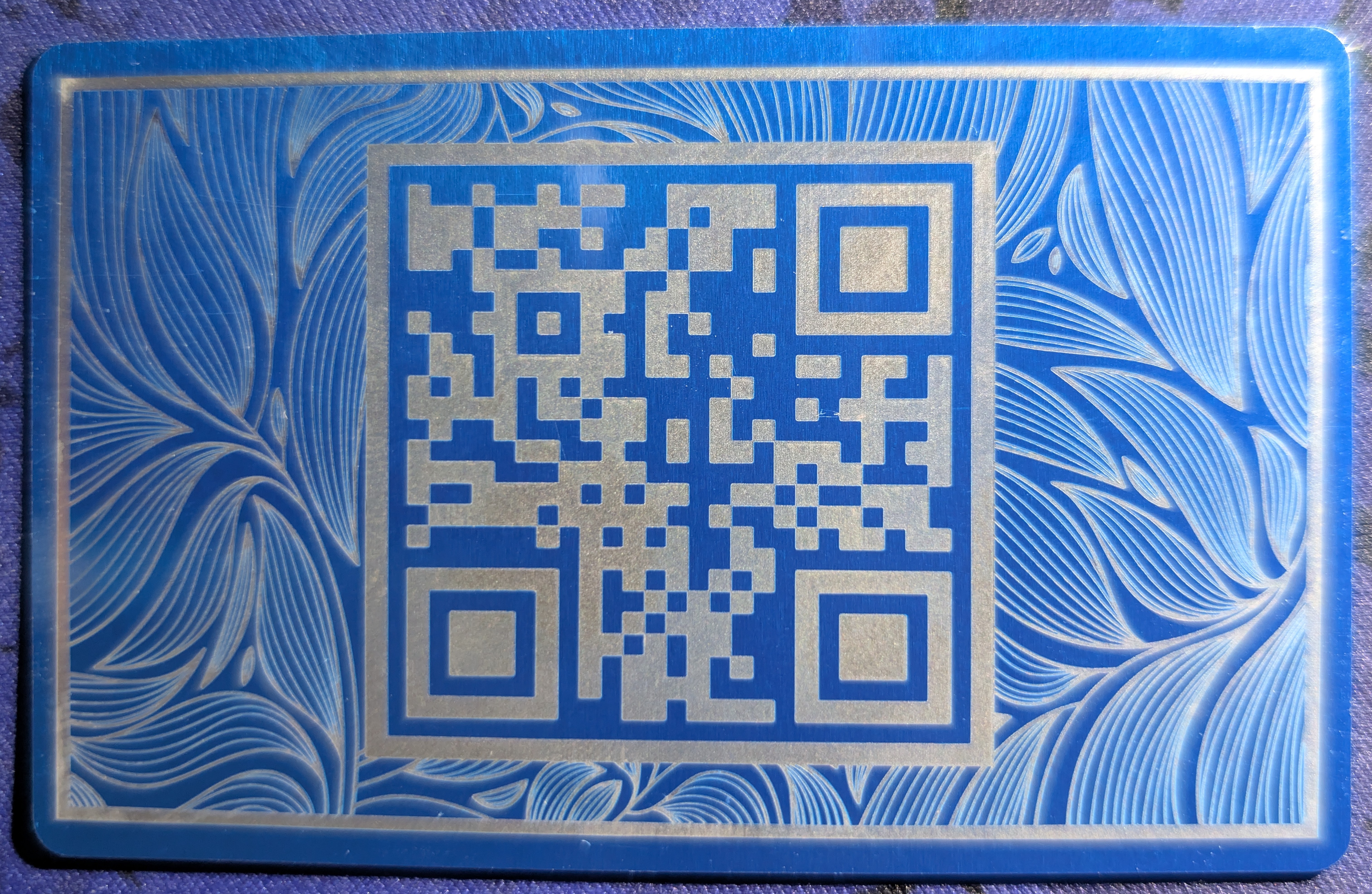 Blue annodized aluminum card with a QR code on the back
